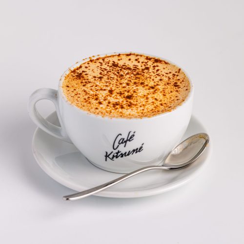 A savory cappuccino with cinnamon, placed in a Cafe Kitsuné cup with a spoon on the side.